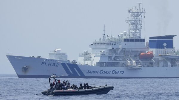 Um barco inflável de casco rígido da Guarda Costeira filipina passa pela Guarda Costeira Japonesa Akitsushima (PLH-32) durante uma perfuração trilateral da Guarda Costeira nas águas na província de Bataan, Filipinas, terça-feira, 6 de junho de 2023 - Sputnik Brasil