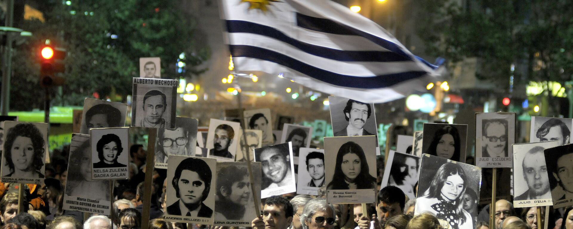 Manifestantes, um deles agitando uma bandeira uruguaia, carregam cartazes com imagens de pessoas desaparecidas durante a ditadura uruguaia de 1973-85 durante uma marcha em Montevidéu, Uruguai - Sputnik Brasil, 1920, 21.06.2023