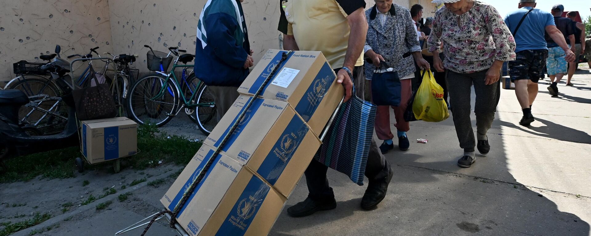 Voluntários distribuem ajuda humanitária do Programa Mundial de Alimentos da ONU, para residentes locais no povoado de Liptsy, região de Carcóvia, 22 de junho de 2023 - Sputnik Brasil, 1920, 22.06.2023