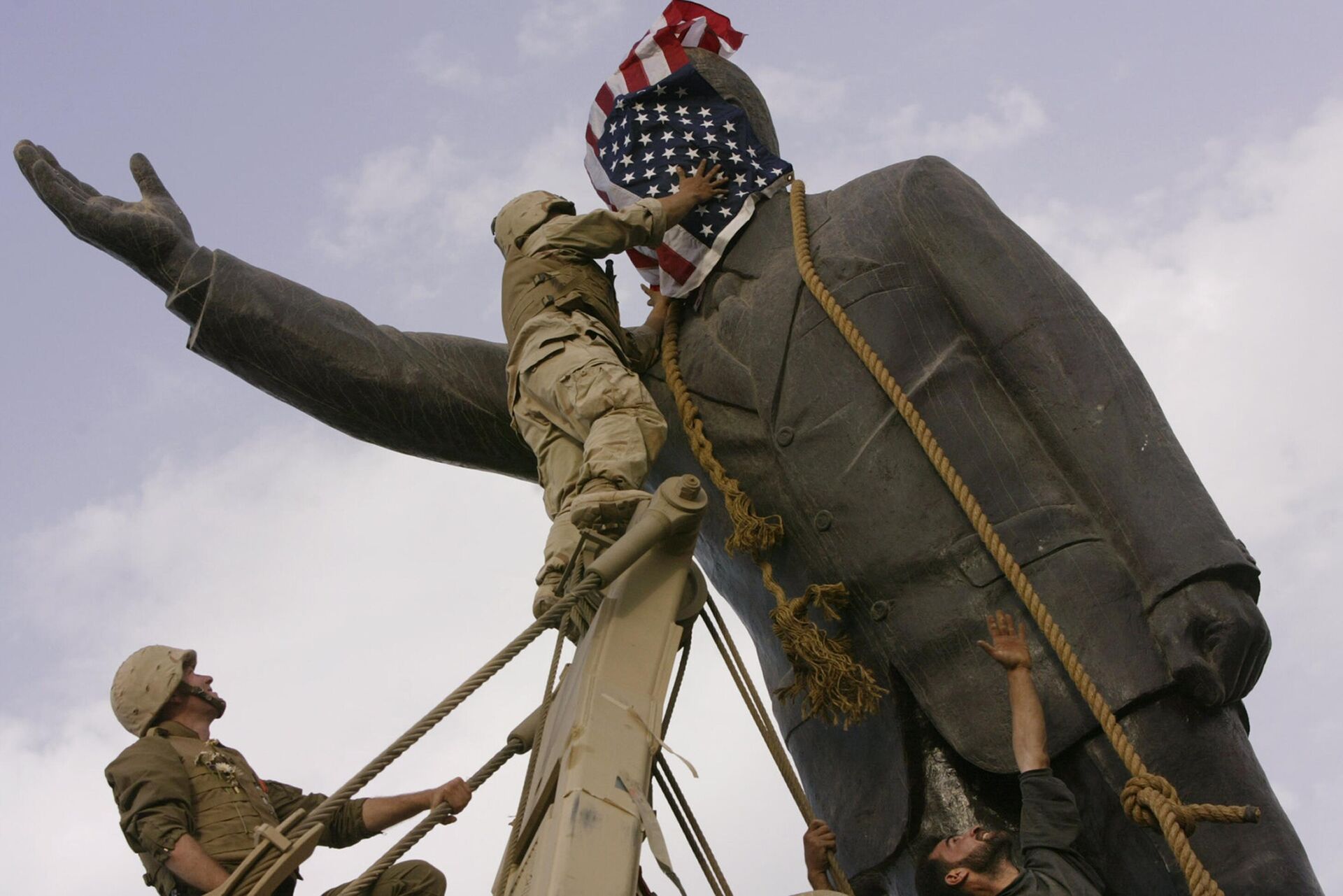 Soldados norte-americanos cobrem o rosto de uma estátua de Saddam Hussein com uma bandeira dos EUA antes de derrubar a estátua no centro de Bagdá no auge da Guerra no Iraque, Iraque, 9 de abril de 2003 - Sputnik Brasil, 1920, 04.10.2023
