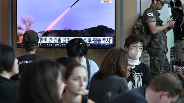 Soldado sul-coreano (à direita) ao lado de uma tela televisiva que exibe um noticiário com imagens de arquivo de um teste de míssil norte-coreano, em uma estação ferroviária em Seul, Coreia do Sul, 22 de julho de 2023 - Sputnik Brasil