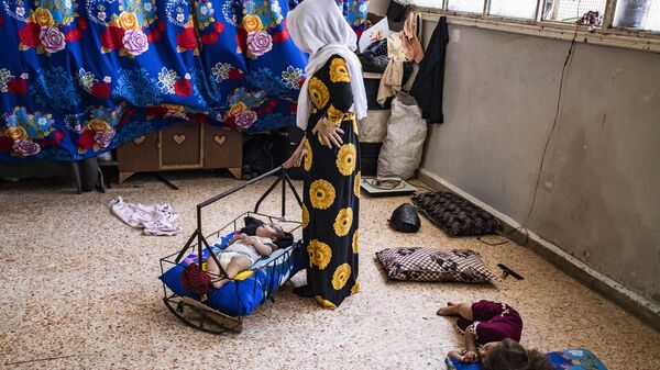 Mãe embala seu bebê para dormir em uma escola que abriga pessoas deslocadas durante onda de calor na província de Al-Hasakah, Síria, em 22 de julho de 2023 - Sputnik Brasil