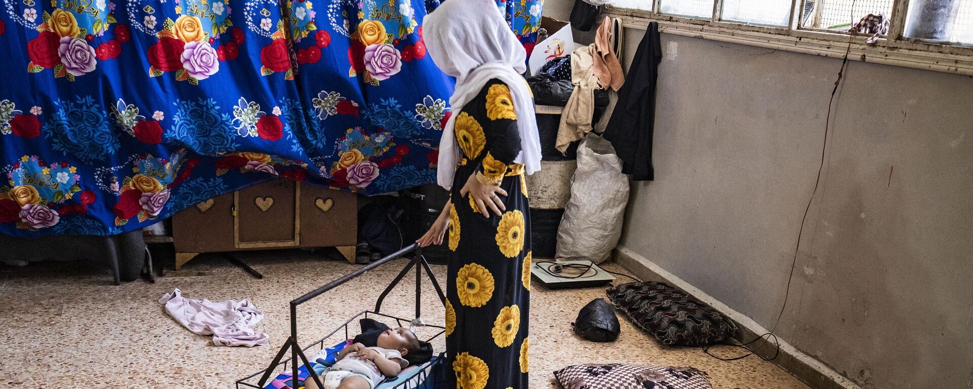 Mãe embala seu bebê para dormir em uma escola que abriga pessoas deslocadas durante onda de calor na província de Al-Hasakah, Síria, em 22 de julho de 2023 - Sputnik Brasil, 1920, 25.07.2023
