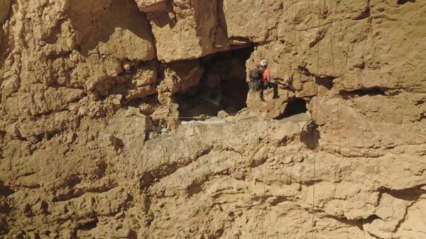 Hagay Hamer, um arqueólogo com o Judean Desert Survey da IAA, desce um penhasco para explorar uma caverna no deserto - Sputnik Brasil