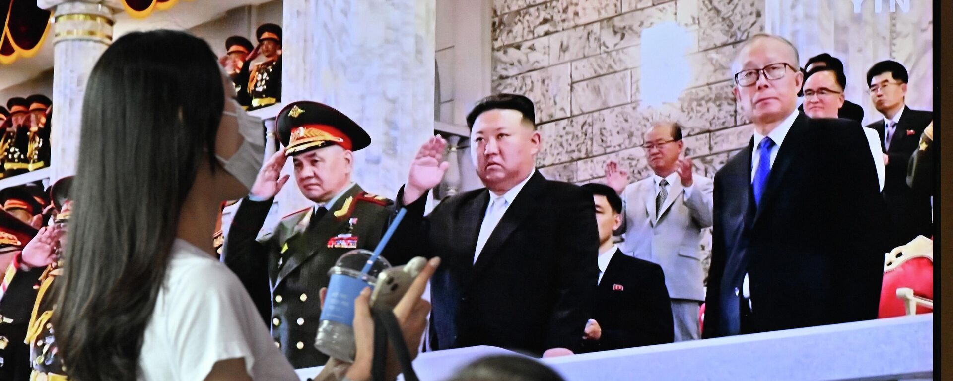 Uma mulher passa por uma tela de televisão mostrando um noticiário com uma imagem do líder norte-coreano Kim Jong Un participando de um desfile militar realizado em Pyongyang para marcar o 70º aniversário do armistício da Guerra da Coreia, em uma estação ferroviária em Seul em 28 de julho de 2023 - Sputnik Brasil, 1920, 28.07.2023