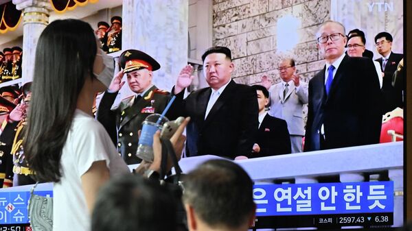Uma mulher passa por uma tela de televisão mostrando um noticiário com uma imagem do líder norte-coreano Kim Jong Un participando de um desfile militar realizado em Pyongyang para marcar o 70º aniversário do armistício da Guerra da Coreia, em uma estação ferroviária em Seul em 28 de julho de 2023 - Sputnik Brasil