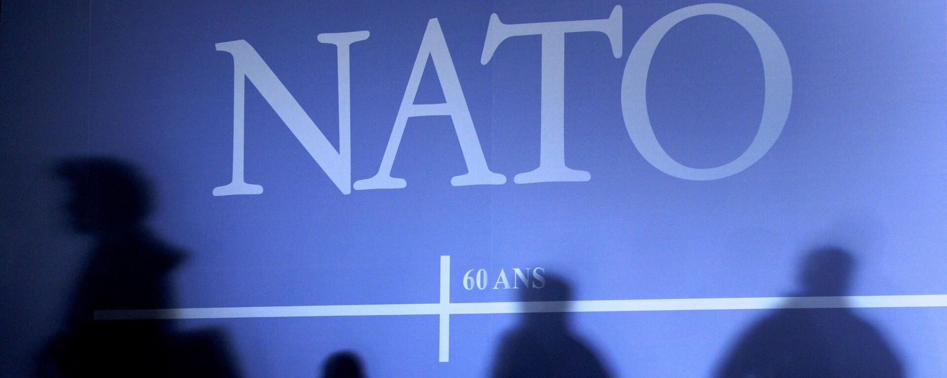 Sombras projetadas em uma parede decorada com o logotipo da OTAN e bandeiras dos países-membros em Estrasburgo, leste da França, antes do início da cúpula da OTAN que marcou o 60º aniversário da organização, 2 de abril de 2009 - Sputnik Brasil, 1920, 10.09.2023