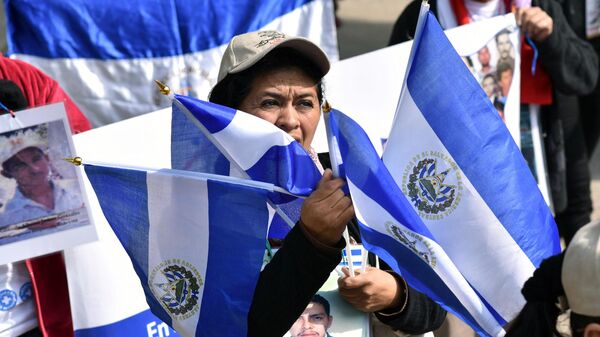 Membro da XIII Caravana de Mães da América Central 4.000 Quilômetros de Busca, Resistência e Esperança, segura bandeiras nacionais do El Salvador durante manifestação em frente à embaixada dos EUA na Cidade do México, México, 14 de dezembro de 2017 - Sputnik Brasil