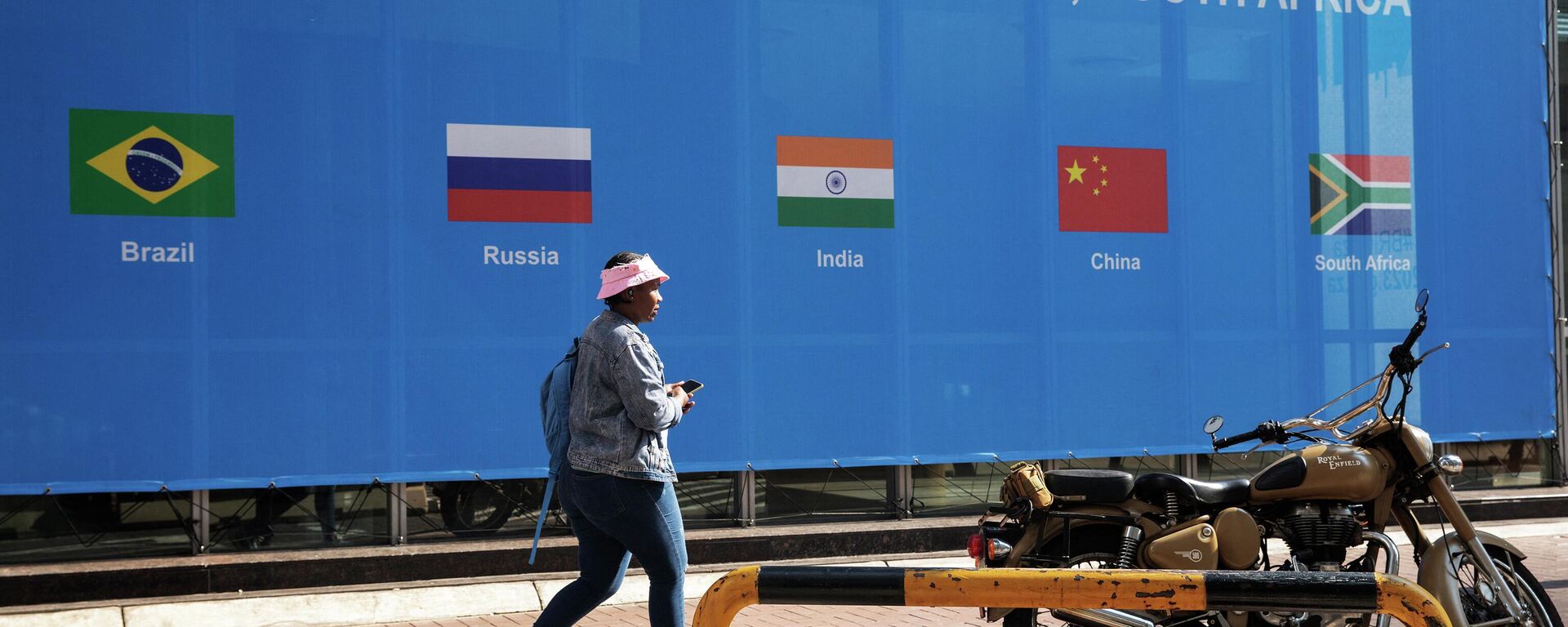 Mulher passa por cartaz do lado de fora do local da Cúpula do BRICS 2023, no Centro de Convenções de Sandton, em Sandton, Joanesburgo, África do Sul, 20 de agosto de 2023 - Sputnik Brasil, 1920, 21.08.2023