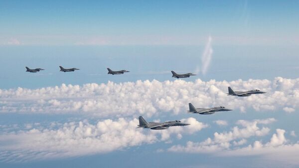 Nesta foto fornecida pelo Estado-Maior Conjunto da Força de Autodefesa Japonesa, três aviões de guerra F-15 da Força de Autodefesa Japonesa, na frente, e quatro caças F-16 das Forças Armadas dos EUA sobrevoam o mar do Japão em 25 de maio de 2022 - Sputnik Brasil
