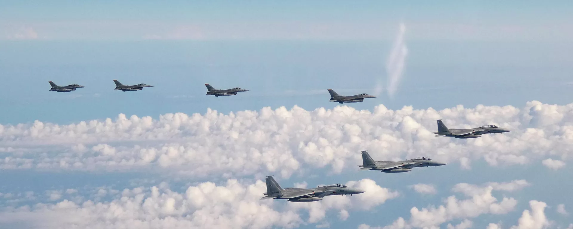 Nesta foto fornecida pelo Estado-Maior Conjunto da Força de Autodefesa Japonesa, três aviões de guerra F-15 da Força de Autodefesa Japonesa, na frente, e quatro caças F-16 das Forças Armadas dos EUA sobrevoam o mar do Japão em 25 de maio de 2022 - Sputnik Brasil, 1920, 14.10.2023