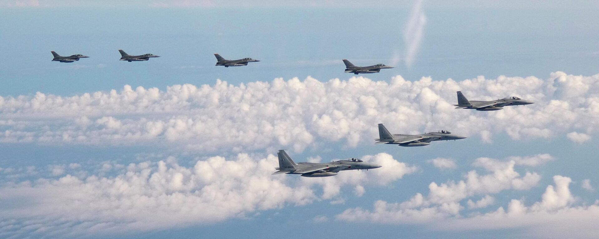 Nesta foto fornecida pelo Estado-Maior Conjunto da Força de Autodefesa Japonesa, três aviões de guerra F-15 da Força de Autodefesa Japonesa, na frente, e quatro caças F-16 das Forças Armadas dos EUA sobrevoam o mar do Japão em 25 de maio de 2022 - Sputnik Brasil, 1920, 25.08.2023