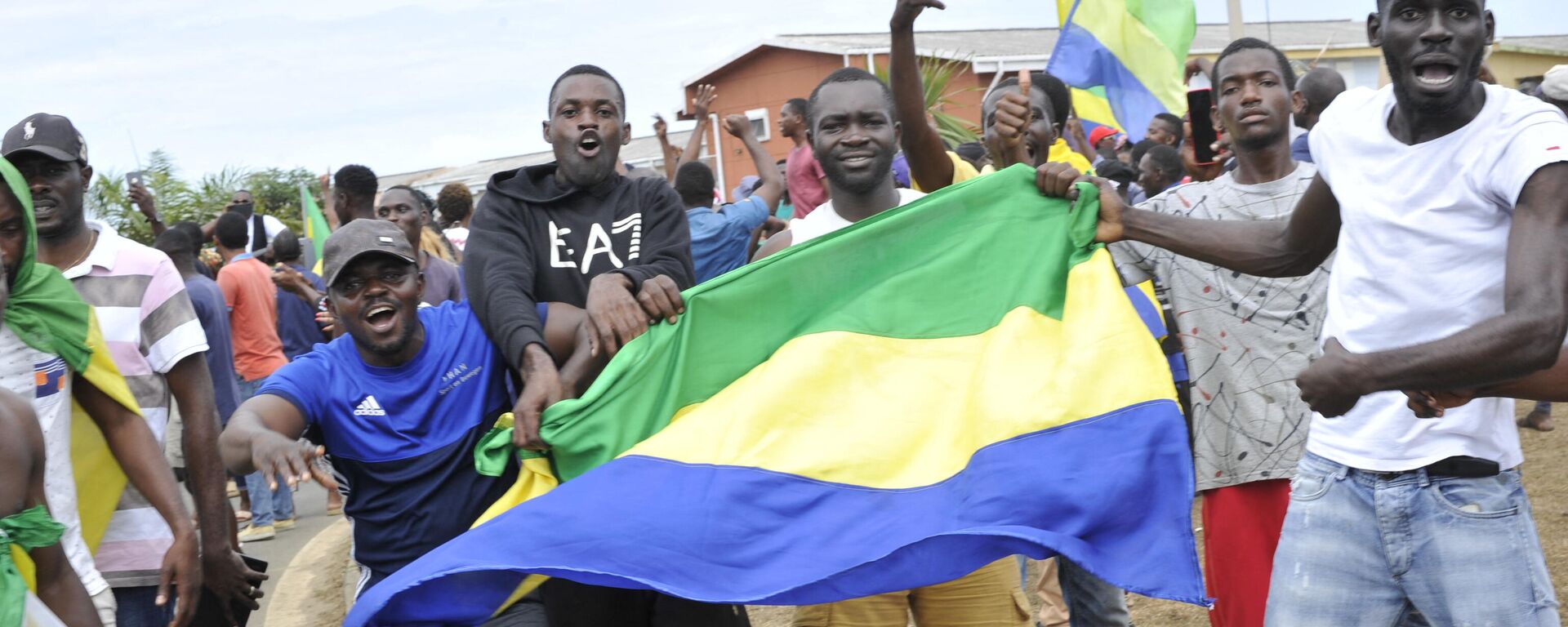 Moradores gesticulam e seguram uma bandeira nacional do Gabão enquanto comemoram em Libreville, em 30 de agosto de 2023 - Sputnik Brasil, 1920, 31.08.2023