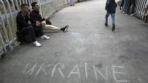 Ucranianos em busca de asilo nos Estados Unidos sentam-se perto de um acampamento no lado mexicano da travessia do porto de San Ysidro, em Tijuana, estado de Baja California, México, 2 de abril de 2022 - Sputnik Brasil