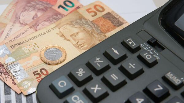Cédulas e moeda de real ao lado de calculadora - Sputnik Brasil