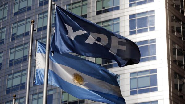 Uma bandeira nacional argentina e um banner representando a empresa petrolífera YPF tremulam do lado de fora da sede da YPF em Buenos Aires, Argentina - Sputnik Brasil