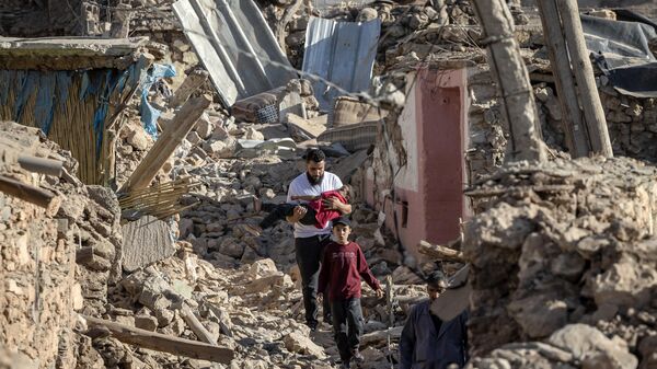 Pessoas passam por casas destruídas após terremoto no vilarejo montanhoso de Tafeghaghte, Marrocos, 9 de setembro de 2023 - Sputnik Brasil