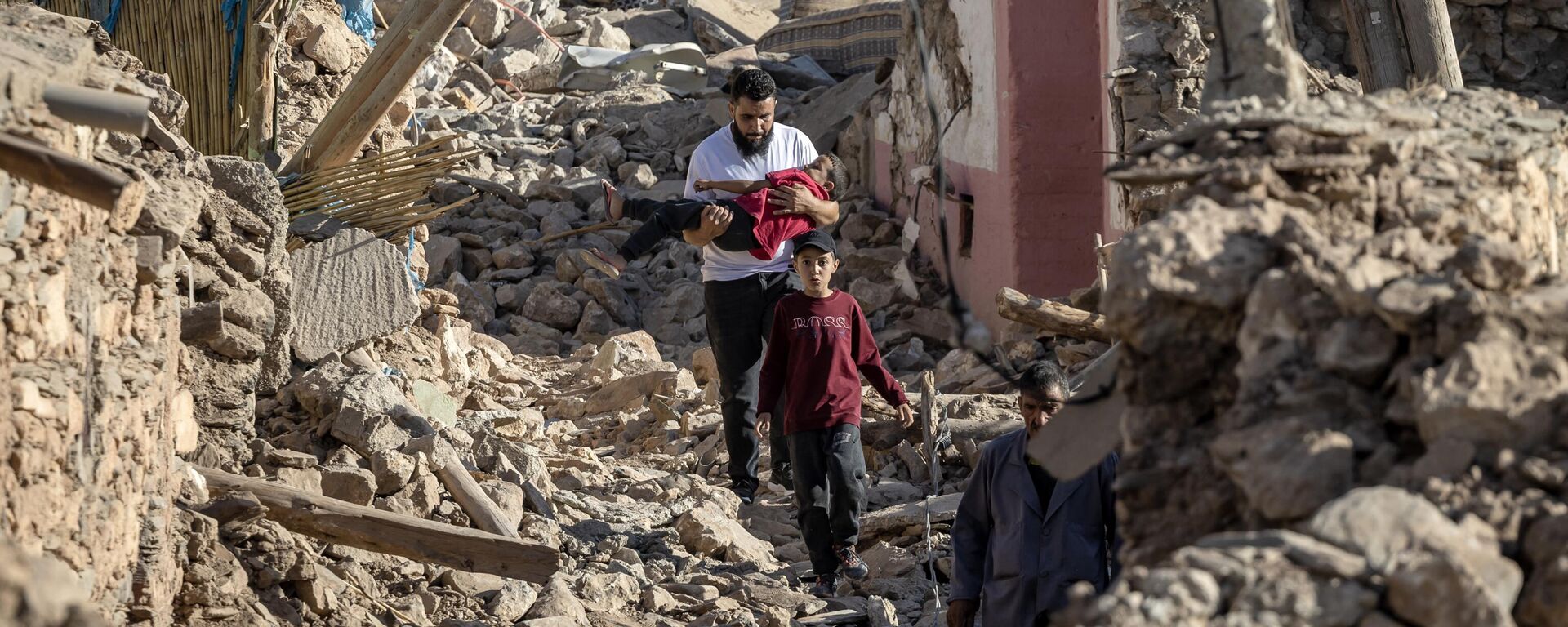 Pessoas passam por casas destruídas após terremoto no vilarejo montanhoso de Tafeghaghte, Marrocos, 9 de setembro de 2023 - Sputnik Brasil, 1920, 09.09.2023