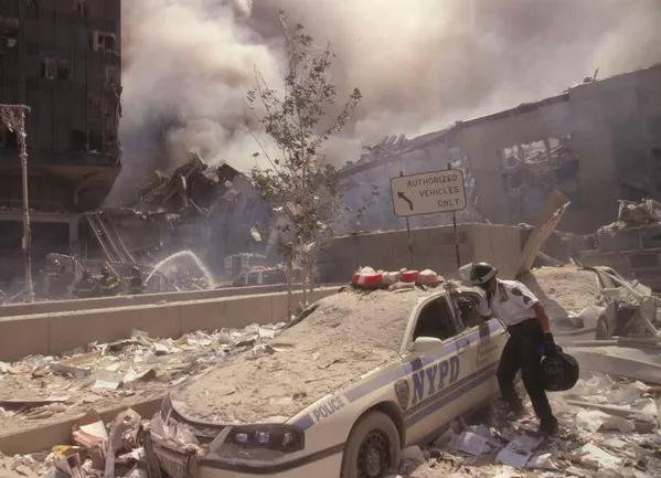Um resgatador entra em um carro da Polícia de Nova York coberto de escombros enquanto bombeiros da cidade pulverizam água em ruínas fumegantes em fundo, após o ataque terrorista de 11 de setembro no World Trade Center. Um resgatador entra em um carro da Polícia de Nova York coberto de escombros enquanto bombeiros da cidade pulverizam água em ruínas fumegantes em fundo, após o ataque terrorista de 11 de setembro no World Trade Center. - Sputnik Brasil