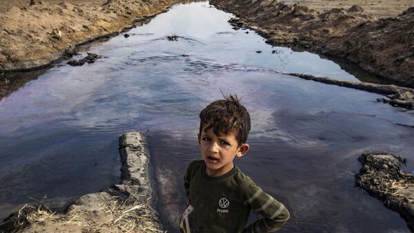 Criança posa para foto às margens de um rio poluído por um campo de petróleo, na zona rural de Rmeilan, na província de Hasakeh, no nordeste da Síria, 14 de agosto de 2023 - Sputnik Brasil