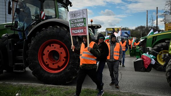 Um agricultor segura uma faixa durante uma ação para bloquear caminhões que atravessam a ponte do Danúbio, marcando a fronteira entre a Bulgária e a Roménia, num protesto contra a importação isenta de impostos de cereais provenientes da Ucrânia para o país a UE, em Rousse, em 29 de março de 2023 - Sputnik Brasil