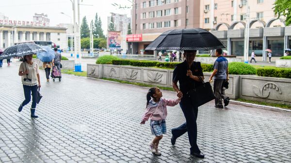 Pedestres usam guarda-chuvas na chuva enquanto caminham do lado de fora da Estação Ferroviária de Pyongyang, em Pyongyang, Coreia do Norte, 20 de setembro de 2023 - Sputnik Brasil