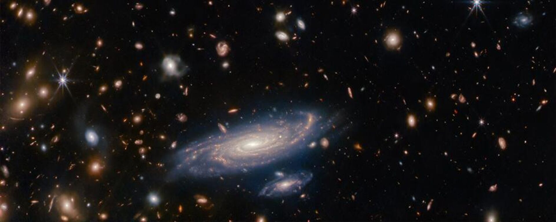 A galáxia em primeiro plano é LEDA 2046648, e é vista há pouco mais de 1 bilhão de anos, enquanto a maioria das outras ficam ainda mais distantes, vistas em um passado distante - Sputnik Brasil, 1920, 08.03.2024