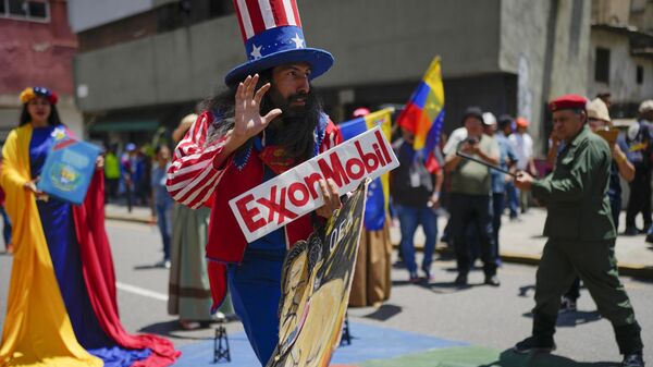 Homem vestido como o personagem norte-americano Tio Sam segura uma placa da petrolífera ExxonMobil durante a marcha pró-governo chamada Recupere o Essequibo, em Caracas. Venezuela, 26 de setembro de 2023 - Sputnik Brasil