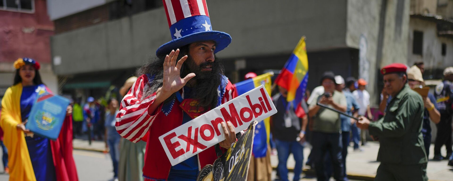 Homem vestido como o personagem norte-americano Tio Sam segura uma placa da petrolífera ExxonMobil durante a marcha pró-governo chamada Recupere o Essequibo, em Caracas. Venezuela, 26 de setembro de 2023 - Sputnik Brasil, 1920, 02.02.2024