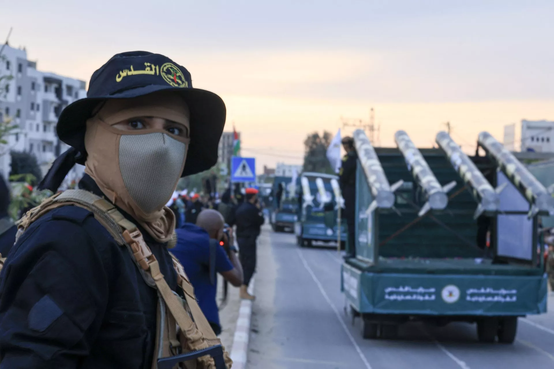 Militante palestino da Jihad Islâmico aparece em desfile do 36º aniversário da fundação do movimento na Cidade de Gaza, em 4 de outubro de 2023, com foguetes em caminhões ao fundo - Sputnik Brasil, 1920, 04.10.2023