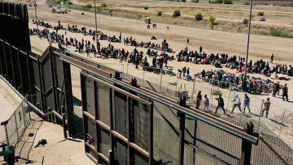 Uma imagem aérea mostra migrantes esperando ao longo do muro da fronteira para se renderem aos agentes da Patrulha de Fronteira da Alfândega e Proteção de Fronteiras dos EUA (CBP, na sigla em inglês) para processamento de pedidos de imigração e asilo após cruzarem o Rio Grande para os Estados Unidos, na fronteira EUA-México, em El Paso, Texas, 10 de maio de 2023 - Sputnik Brasil