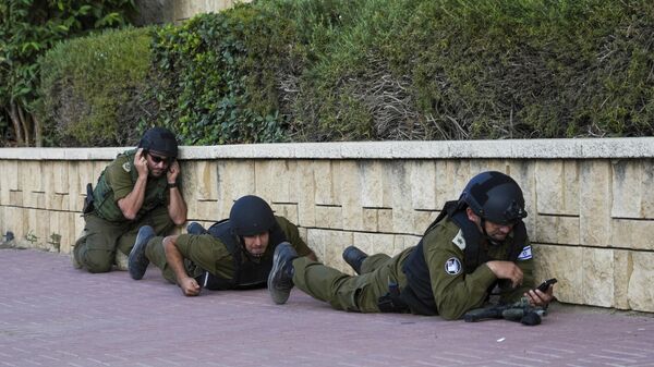 Soldados israelenses se protegem enquanto uma sirene soa um alerta sobre a chegada de foguetes disparados da Faixa de Gaza, em Ashkelon, Israel, 10 de outubro de 2023 - Sputnik Brasil