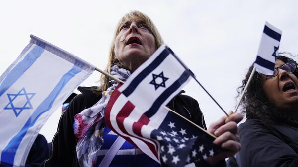Um apoiador segura bandeiras israelenses e americanas em um evento de solidariedade em Glencoe. Illinois, 10 de outubro de 2023 - Sputnik Brasil