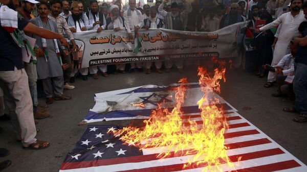 Apoiadores da Fundação Palestina Paquistão queimam representações das bandeiras israelense e americana enquanto entoam slogans contra os ataques aéreos israelenses em Gaza durante uma manifestação para mostrar solidariedade ao povo palestino, em Karachi, Paquistão, 8 de outubro de 2023 - Sputnik Brasil