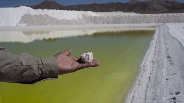 Trabalhador da mina de lítio Albemarle mostra pedaço de sal perto de uma piscina de salmoura altamente concentrada em lítio no Deserto do Atacama. Chile, 17 de abril de 2023 - Sputnik Brasil