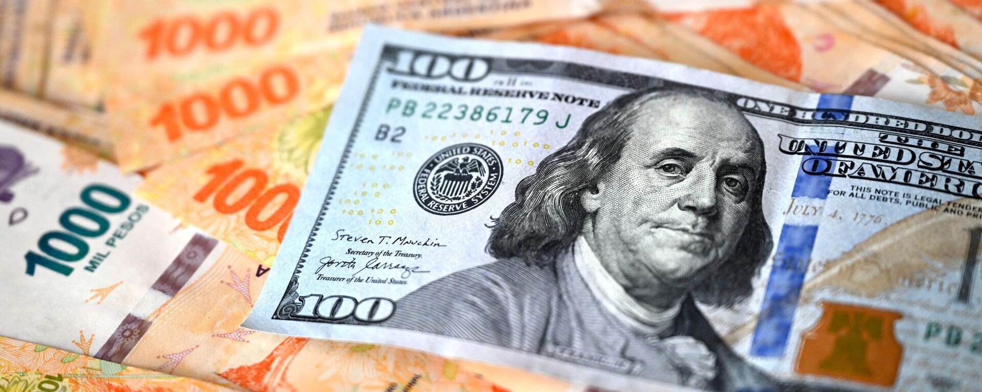 Esta imagem ilustrativa mostra uma nota de 100 dólares americanos em cima de pesos argentinos, em Buenos Aires, em 10 de outubro de 2023 - Sputnik Brasil, 1920, 11.10.2023