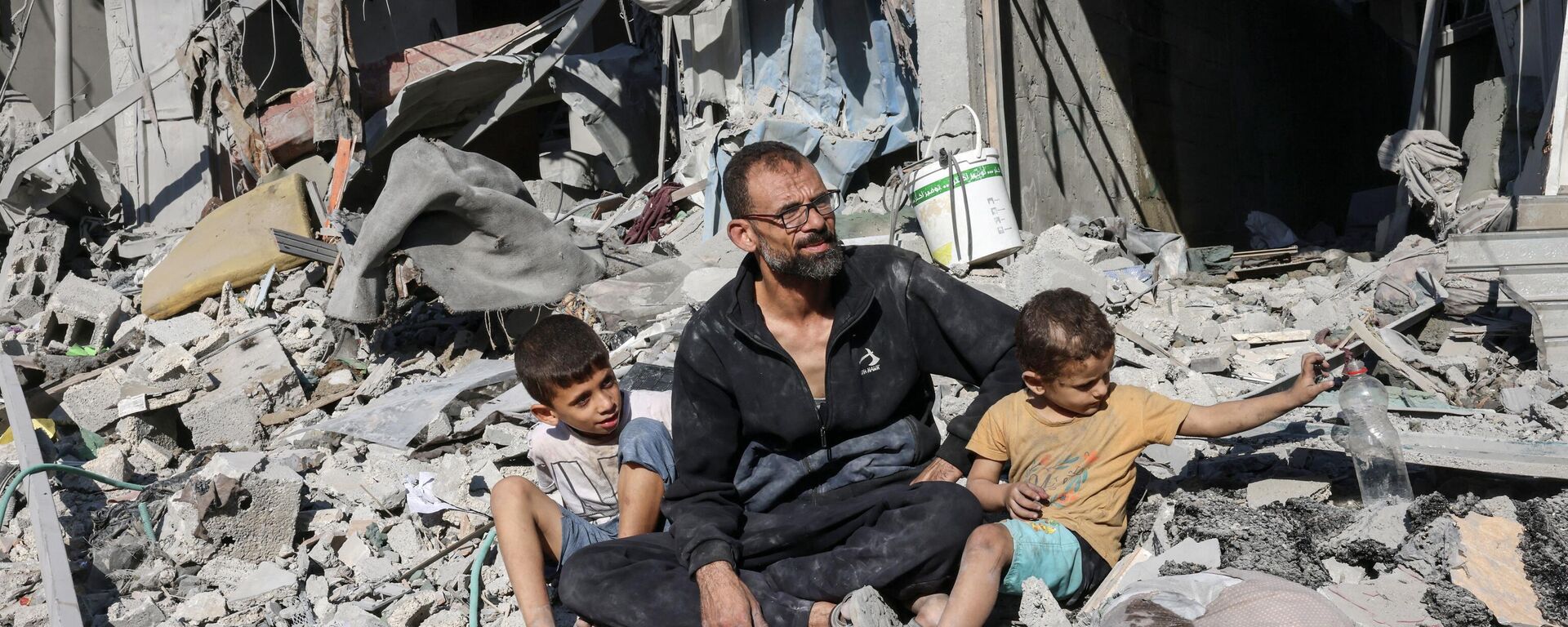 Homem palestino sentado com membros de sua família do lado de fora de um prédio destruído por um ataque aéreo israelense em Rafah, no sul da Faixa de Gaza, em 12 de outubro de 2023 - Sputnik Brasil, 1920, 31.10.2023