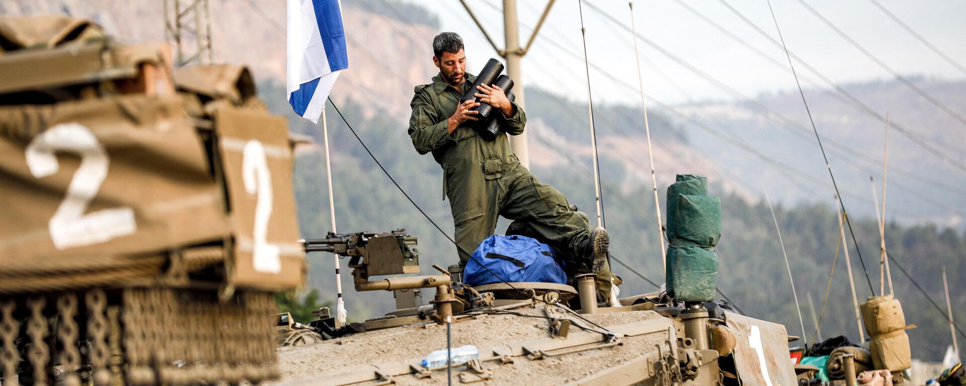 Soldado do Exército israelense segura projéteis no alto de um tanque Merkava, em meio a concentração de tanques na alta Galileia, no norte de Israel, perto da fronteira com o Líbano, em 11 de outubro de 2023 - Sputnik Brasil, 1920, 21.10.2023