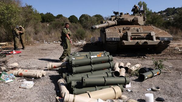 Soldados israelenses estão perto de um tanque Merkava enquanto ocupam uma posição em um local não revelado na fronteira com o Líbano em 21 de outubro de 2023 - Sputnik Brasil