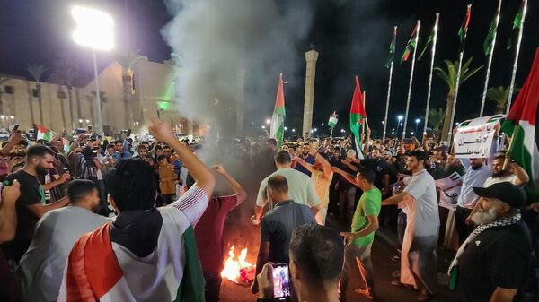 Manifestantes queimam uma bandeira dos EUA durante um protesto na capital da Líbia, Trípoli, em 17 de outubro de 2023, em apoio aos palestinos, depois que um ataque aéreo atingiu o hospital batista al-Ahli, no centro de Gaza, matando centenas de pessoas - Sputnik Brasil