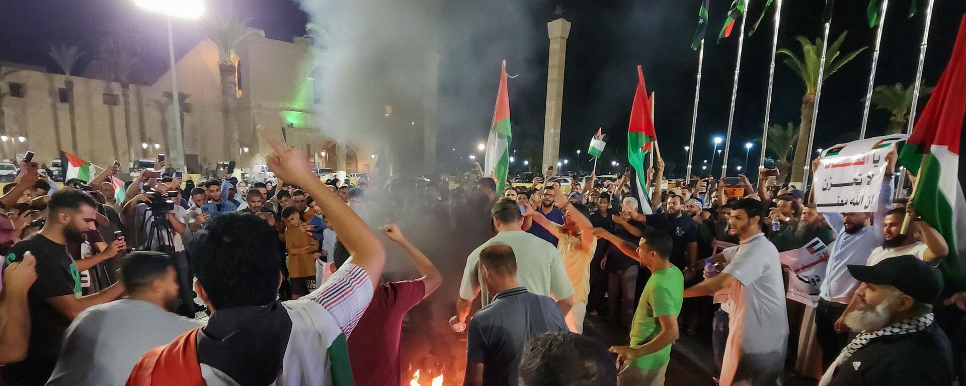 Manifestantes queimam uma bandeira dos EUA durante um protesto na capital da Líbia, Trípoli, em 17 de outubro de 2023, em apoio aos palestinos, depois que um ataque aéreo atingiu o hospital batista al-Ahli, no centro de Gaza, matando centenas de pessoas - Sputnik Brasil, 1920, 26.10.2023
