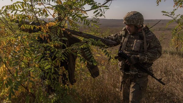 Soldado ucraniano da 65ª Brigada Mecanizada olha para jaqueta militar presa a cruz. Zaporozhie, 1º de outubro de 2023 - Sputnik Brasil