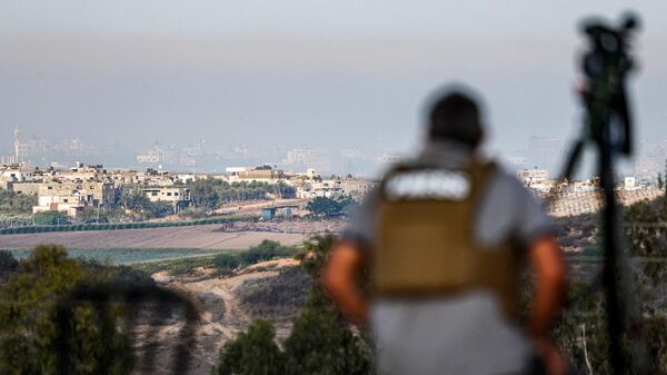Jornalista com câmera observa a parte norte da Faixa de Gaza desde a cidade de Sderot, no sul de Israel, em 18 de outubro de 2023 - Sputnik Brasil