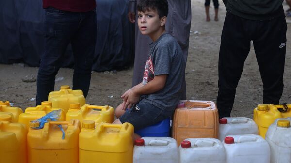 Menino com galões espera em fila para comprar água, em Rafah, na Palestina - Sputnik Brasil