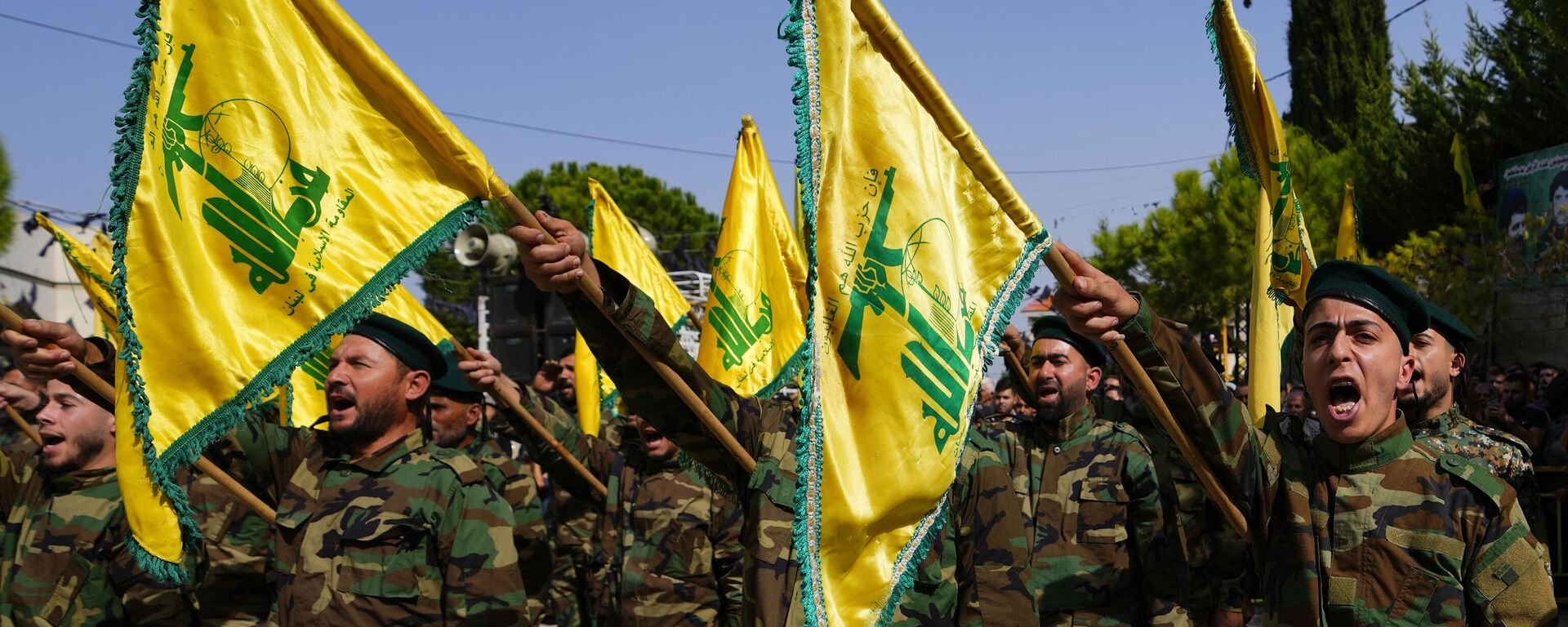 Os combatentes do Hezbollah levantam a bandeira de seu grupo e gritam slogans enquanto assistem ao cortejo fúnebre do combatente do Hezbollah, Bilal Nemr Rmeiti, que foi morto por bombardeios israelenses, domingo, 22 de outubro de 2023 - Sputnik Brasil, 1920, 24.12.2023