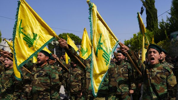 Os combatentes do Hezbollah levantam a bandeira de seu grupo e gritam slogans enquanto assistem ao cortejo fúnebre do combatente do Hezbollah, Bilal Nemr Rmeiti, que foi morto por bombardeios israelenses, domingo, 22 de outubro de 2023 - Sputnik Brasil