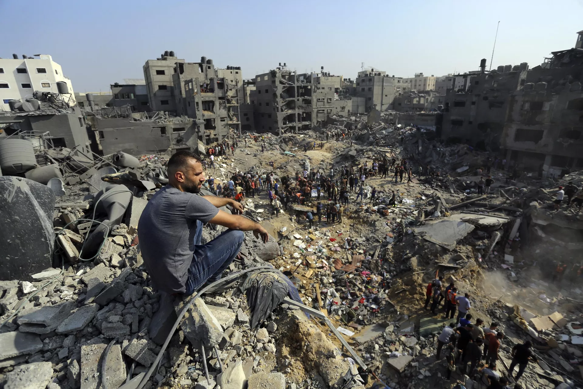 Homem senta-se sobre os escombros enquanto outros passeiam entre os destroços de edifícios alvos de ataques aéreos israelenses no campo de refugiados de Jabaliya, no norte da Faixa de Gaza, 1º de novembro de 2023 - Sputnik Brasil, 1920, 09.11.2023