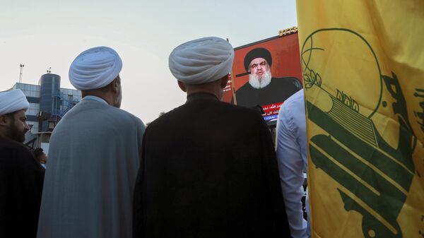 Manifestantes iraquianos assistem a um discurso do líder do Hezbollah do Líbano, Sayyed Hassan Nasrallah, em uma tela enquanto seguram bandeiras do Hezbollah durante um comício pró-Palestina em Basra, Iraque, 3 de novembro de 2023 - Sputnik Brasil