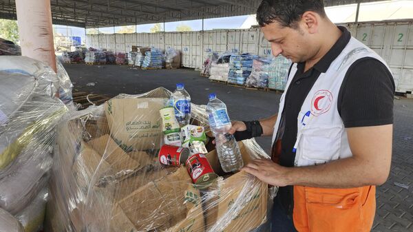 Trabalhadores das Nações Unidas e do Crescente Vermelho preparam ajuda para a distribuição aos palestinos no armazém da UNRWA, em Deir al-Balah, Faixa de Gaza, 23 de outubro de 2023 - Sputnik Brasil