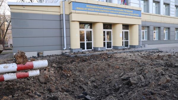 Uma cratera decorrente de explosão em frente a uma escola como resultado do bombardeio de Donetsk pelas Forças Armadas Ucranianas. Donetsk, 15 de dezembro de 2023 - Sputnik Brasil